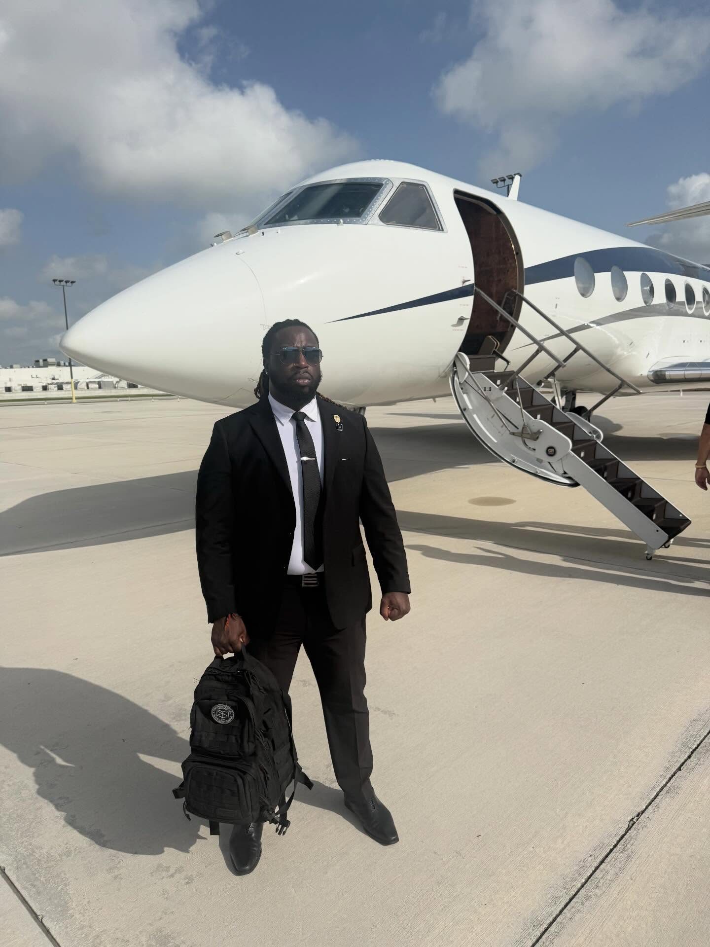Suited Spectrum executive protection agent in front of a private jet