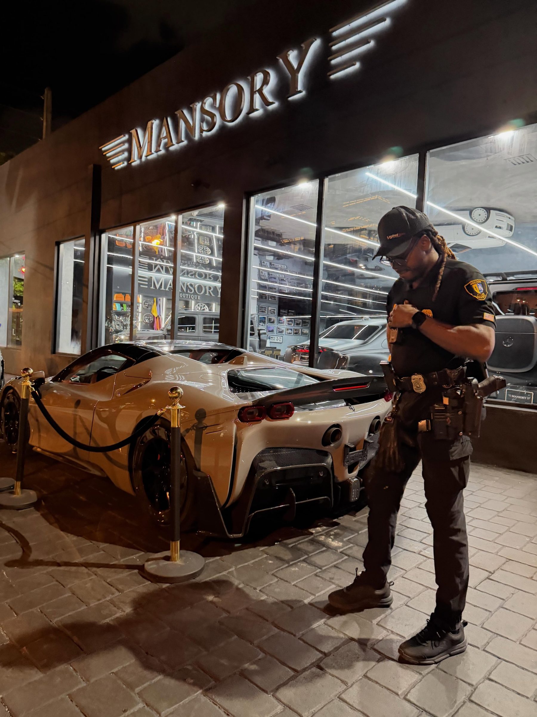 Armed Spectrum guard outside a Mansory supercar showroom with a Ferrari SF90
